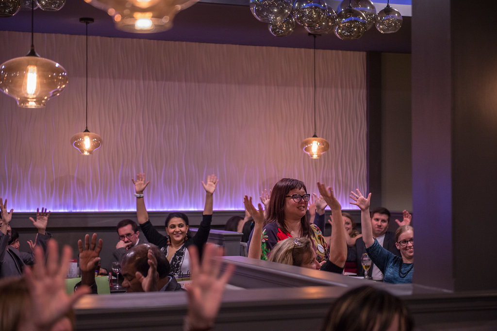 Participants waving hands at Cahoots Theatre SIGNature Gala